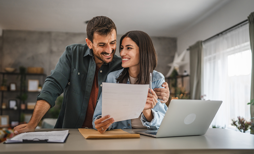 Smiling couple with laptop and papers