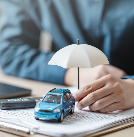Miniature car and umbrella on paperwork