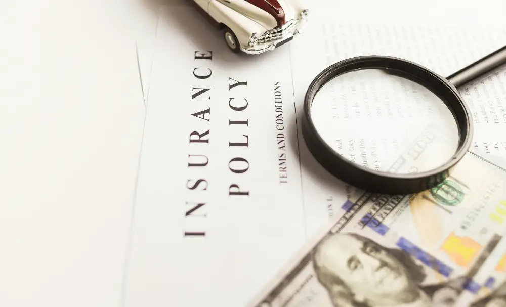 Close-up of an insurance policy document with money and a magnifying glass.